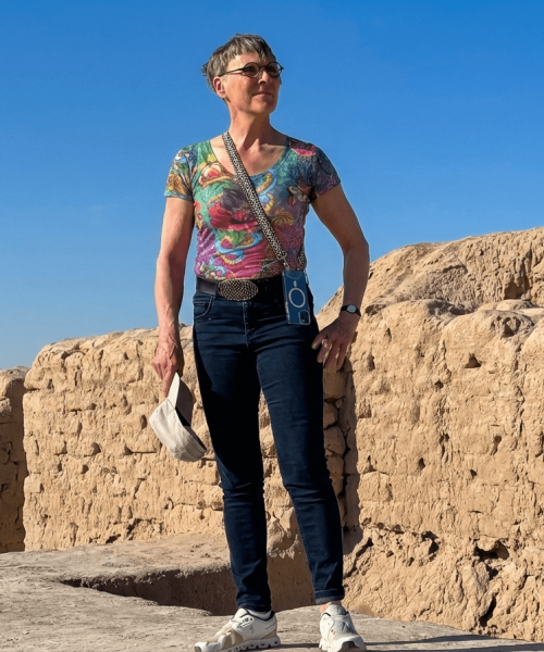 Reisende vor historischen Ruinen aus Lehmziegeln bei sonnigem Wetter.